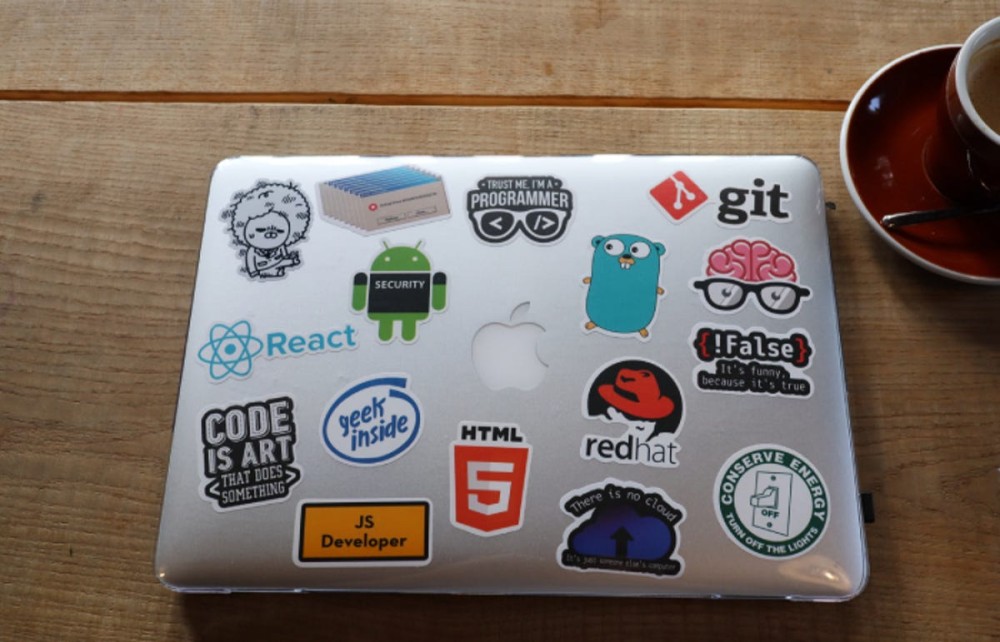 a closed Apple laptop covered in stickers