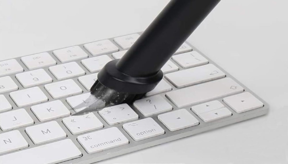 a small vacuum with a brush is sucking up dirt from a computer keyboard