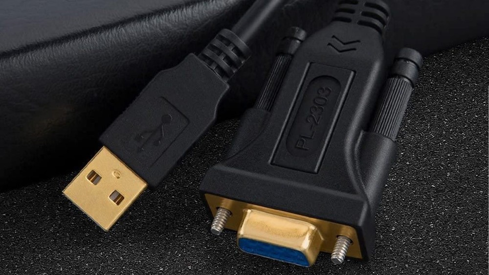 a USB to serial cable adapter that's black and gold and resting on a black surface