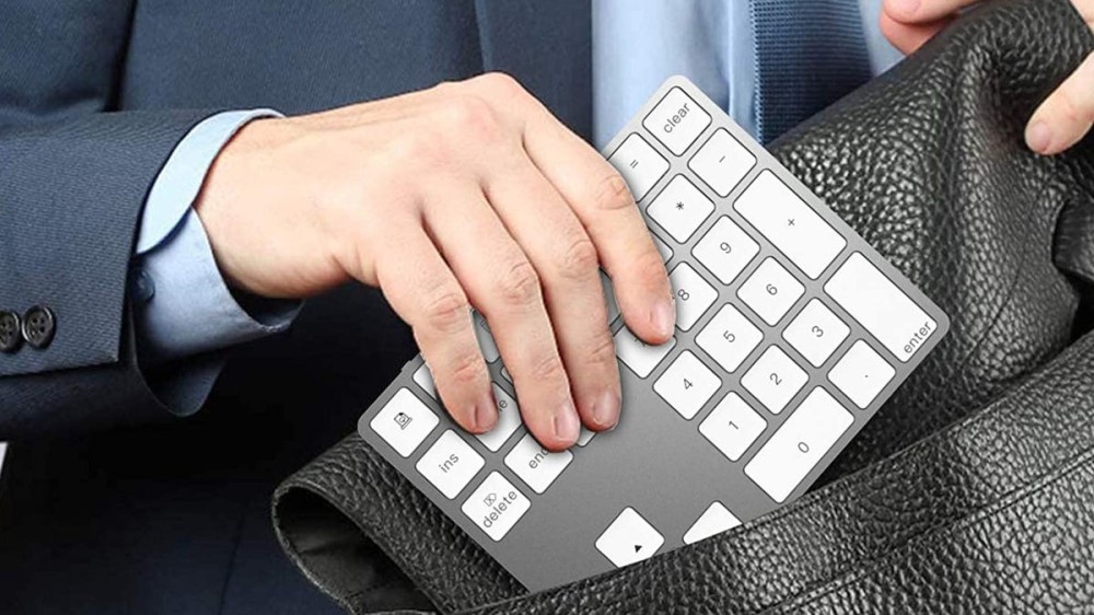 A man storing a numeric keypad in his travel bag