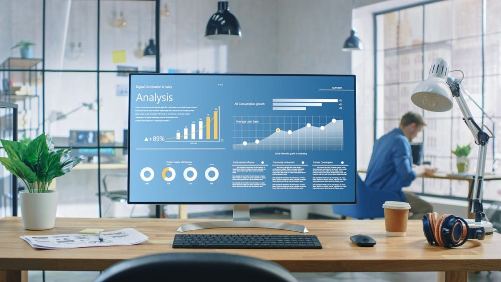 A monitor displays an analysis slide on a desk in a modern office.