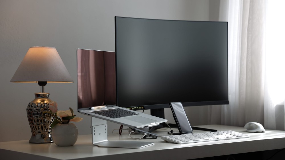 A curved monitor set up on a desk by a laptop.