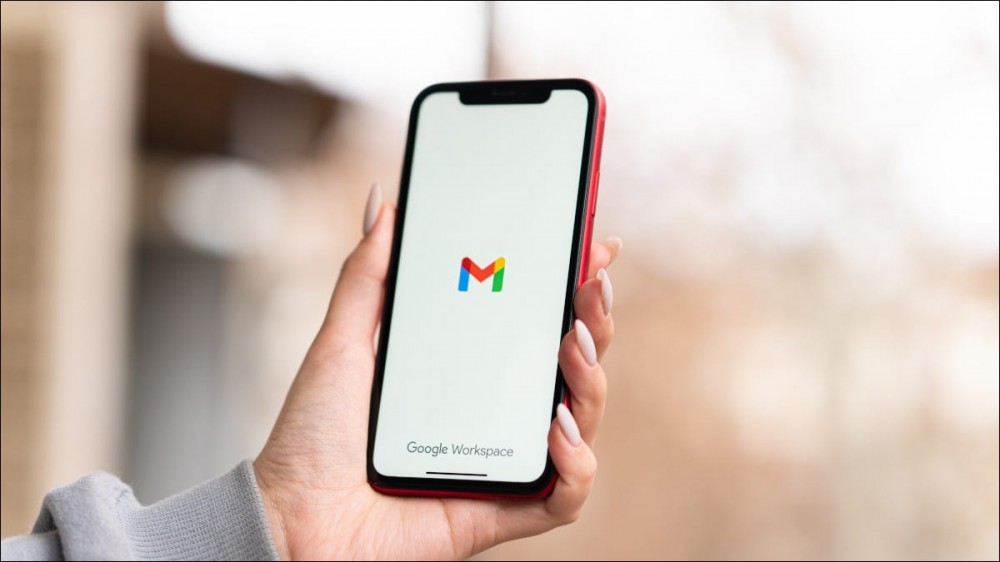 Woman's hand holding an iPhone with the Gmail logo on display.