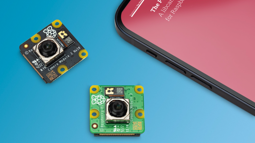 The Raspberry Pi Camera Module 3 and Camera Module 3 NoIR on a table next to a smartphone.