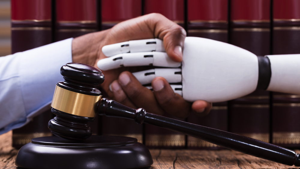 A man and a robot shaking hands over a gavel.