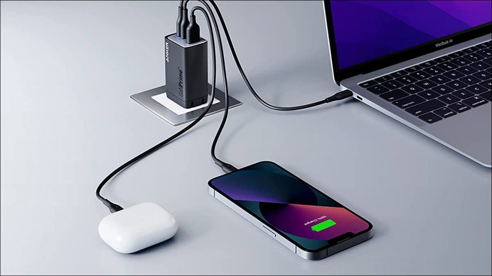 A premium Anker high power charger with an iPhone, AirPods, and MacBook plugged in.