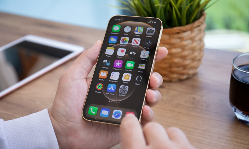 person using iPhone with iPad on table in background