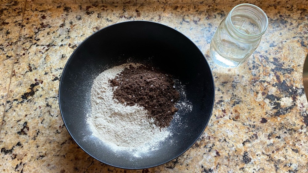 Kitchen counter with a glass of water and a bowl with clay and potting soil in it